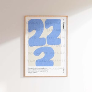 May include: A light blue and white abstract art print with the number 22 in large, bold, handwritten font. The print is framed in a light wood frame and has the text "Alignment" and "Designed and Drawn by Ashley Yamakawa" on the right side. The text "Two suggests balance, trust, and alignment. Experiencing two in a sequence (either within a set of three, four, or within a pattern) could mean that someone - either in the physical realm or spiritual domain - is helping you get where you need to go." is at the bottom of the print.