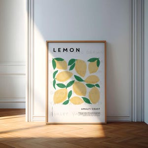 May include: A white poster with the word "LEMON" in black text at the top. The poster features a watercolor illustration of lemons with green leaves. The text "Amalfi Coast" is at the bottom of the poster.