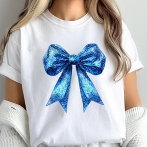 May include: A white t-shirt with a blue glitter bow design.