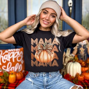 May include: Black t-shirt with a graphic of a pumpkin with a leopard print bow and the word "MAMA" repeated three times.