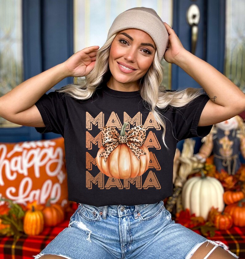 May include: Black t-shirt with a graphic of a pumpkin with a leopard print bow and the word "MAMA" repeated three times.