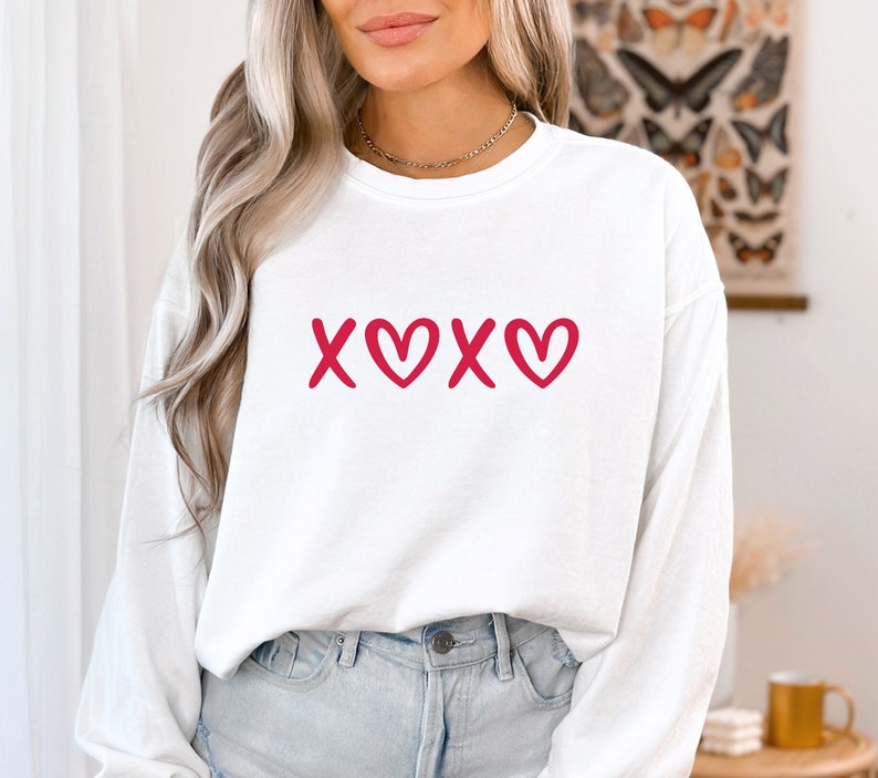 May include: White long-sleeve sweatshirt with a red "XOXO" graphic featuring hearts.