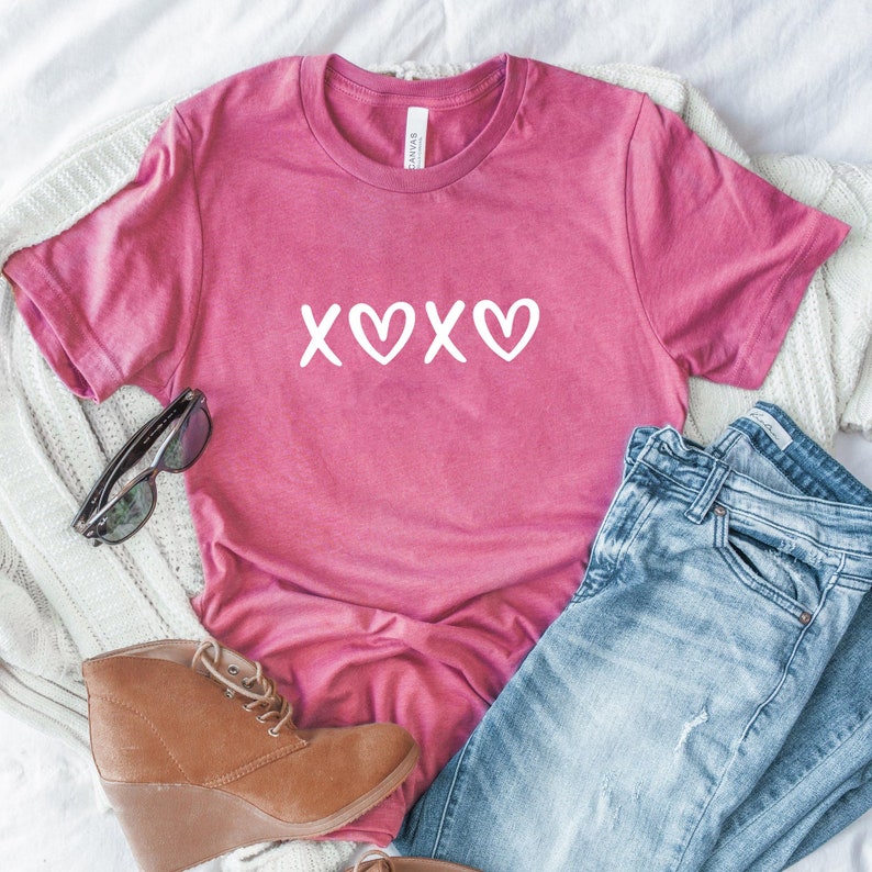 May include: A pink t-shirt with a white graphic that says "XOXO" with hearts in place of the Os.
