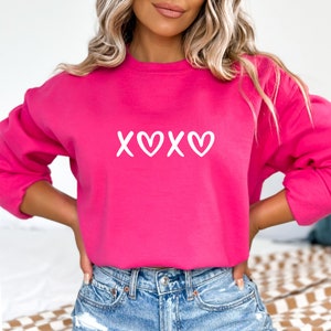 May include: A pink sweatshirt with a white "XOXO" graphic on the front.