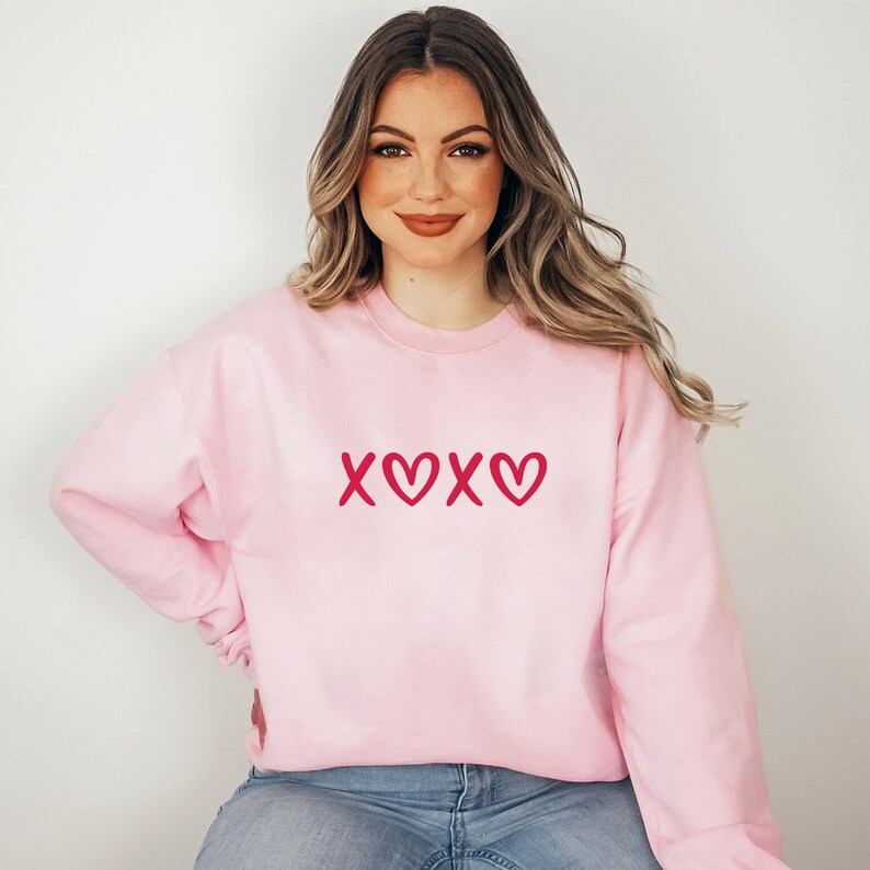 May include: A pink sweatshirt with a red "XOXO" graphic on the front.
