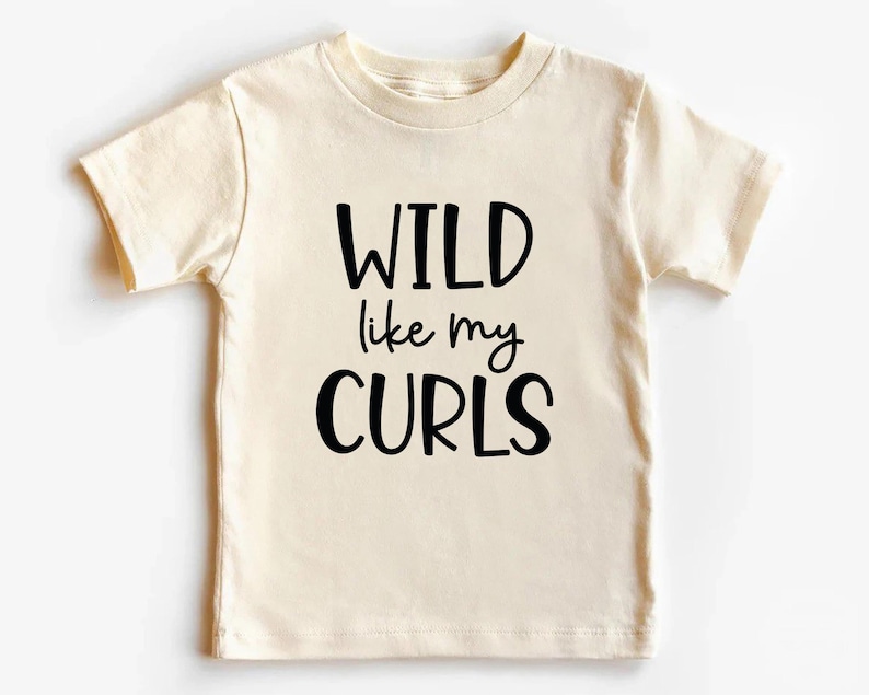 May include: A cream colored short-sleeved t-shirt with black text that reads "WILD like my CURLS".