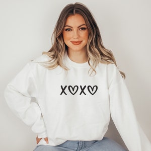 May include: White sweatshirt with a black graphic that says "XOXO" with hearts.