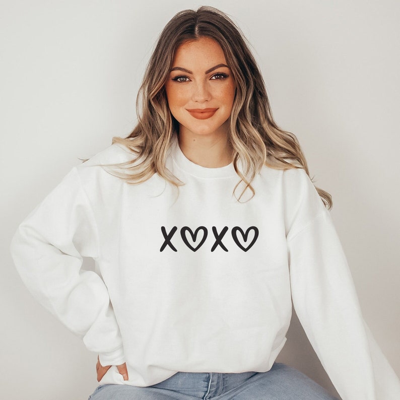 May include: White sweatshirt with a black graphic that says "XOXO" with hearts.