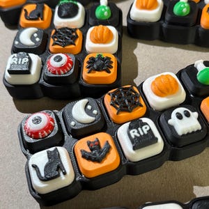 Pode incluir: Um conjunto de teclas de teclado com tema de Halloween com vários designs. As teclas incluem abóboras, aranhas, morcegos, fantasmas e lápides. As teclas são pretas, brancas, laranja e verdes.