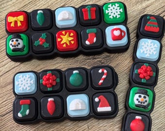 May include: Black rectangular trays with Christmas-themed designs. Each square features a different festive icon, including a snowman, gift, snowflake, and candy cane. The icons are in various colors, such as red, green, and white.