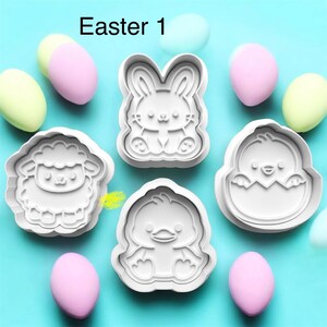 May include: White plastic Easter-themed cookie cutters in the shapes of a bunny, lamb, chick, and duckling. The image includes pastel-colored eggs and the text "Easter 1" on a light blue background.
