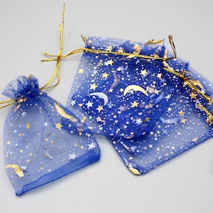 Puede incluir: Bolsas de regalo de organza azul con estrellas doradas y medias lunas. Las bolsas tienen cierres de cordón dorado.