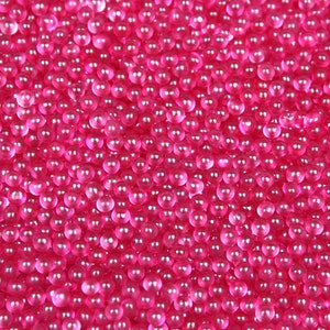 May include: A close-up image of a large quantity of small, pink, round, translucent beads.