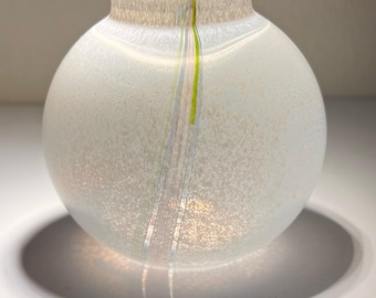 May include: A white glass vase with a textured surface and a single stripe of green and white running down the centre.