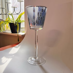 Peut inclure: Un gobelet en verre transparent avec une longue tige et un large bol. Le bol présente un motif bleu et or de formes abstraites.