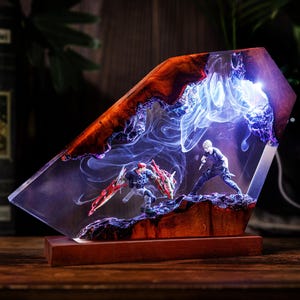 Op de afbeelding: Een unieke hars sculptuur met twee actiefiguren in een gevechtsscène, tegen een achtergrond van wervelende blauwe en witte lichteffecten. De sculptuur heeft een houten basis en een heldere, schuine hars top met een roodbruine rand.