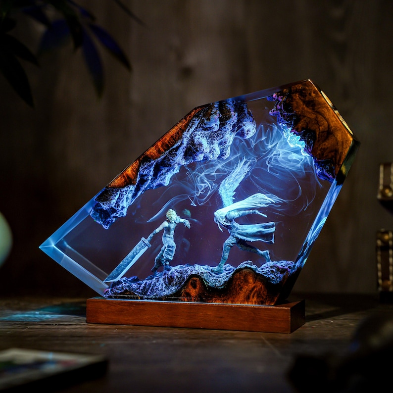 May include: A rectangular resin art piece featuring a battle scene with two figures, illuminated by blue light. The artwork is encased in clear resin with a wooden base and accents. The edges have a brown, textured appearance.