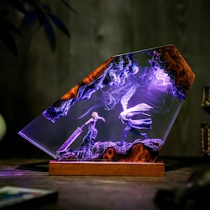 May include: A decorative resin sculpture featuring a battle scene with two figures, illuminated by purple light. The sculpture has a wooden base and a clear, angled resin body with wood and purple accents. The figures are in a fighting pose.
