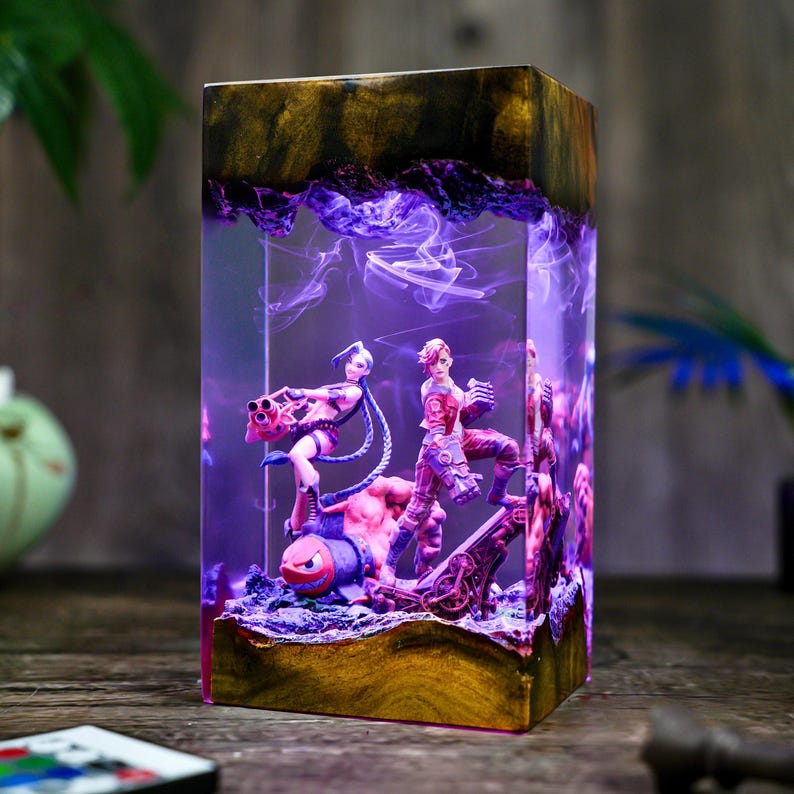 May include: A rectangular resin lamp featuring a scene with multiple figurines. The lamp has a gold and brown top and base, with a purple and blue interior. The figurines depict characters in action poses.