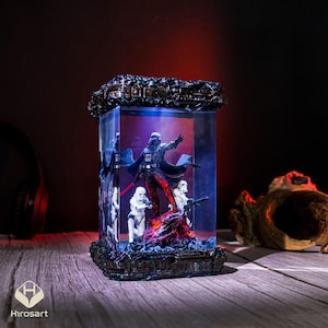 K&ouml;nnte beinhalten: Eine gl&auml;serne Vitrine mit einer schwarzen und roten Darth Vader Figur und zwei wei&szlig;en Stormtrooper Figuren. Die Vitrine ist von innen mit blauem Licht beleuchtet und hat einen schwarzen Sockel.