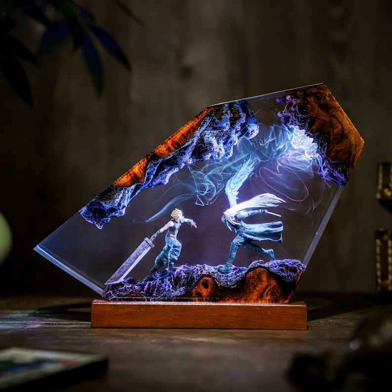May include: A resin art piece featuring two figures in combat, set against a backdrop of swirling blue and white light. The artwork is encased in a clear, angled resin block with a wooden base, showcasing a detailed fantasy scene.