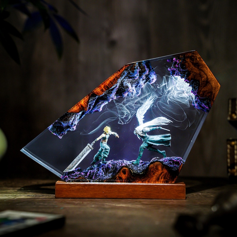May include: A resin art piece depicting a battle scene with two figures, one with a large sword. The artwork is encased in a clear, angled resin block with a wooden base. The top edges feature a mix of orange, blue, and purple hues.