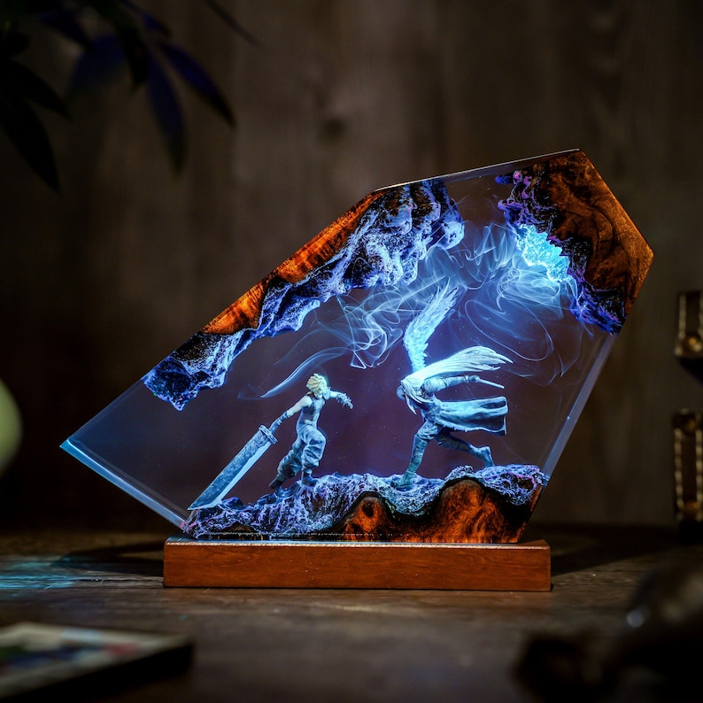 May include: A resin art piece featuring two figures in a battle scene, set within a clear, angled block. The artwork has a wooden base and incorporates blue and orange hues, with a glowing effect. The figures are in a dynamic pose, suggesting action.