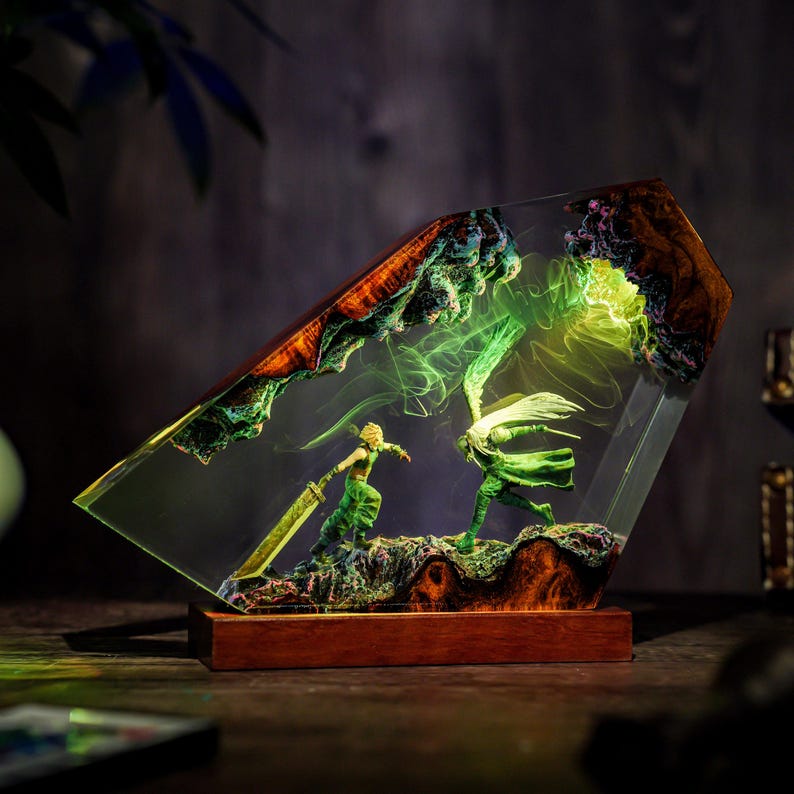 May include: A detailed resin sculpture featuring two figures in a battle scene, set within a clear, angled block. The figures are green, with one wielding a large sword. The base is a dark wood, and the scene is illuminated with green light.