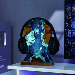 May include: A black headphone stand with a galaxy-themed resin base. The base features a spaceship and a glowing blue and green nebula design.