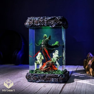 K&ouml;nnte beinhalten: Eine dunkle, detaillierte Harzfigur von Darth Vader und zwei Sturmtruppen in einer durchsichtigen Glaskuppel mit gr&uuml;nem Licht. Die Figur steht auf einem schwarzen Sockel mit einer strukturierten Oberfl&auml;che.