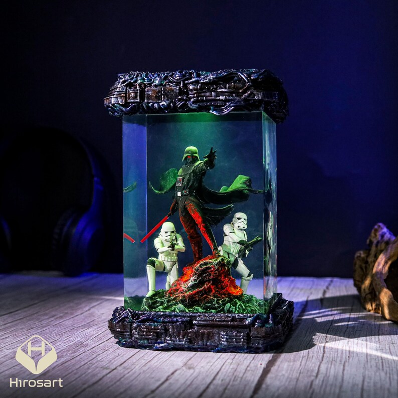 K&ouml;nnte beinhalten: Eine dunkle, detaillierte Harzfigur von Darth Vader und zwei Sturmtruppen in einer durchsichtigen Glaskuppel mit gr&uuml;nem Licht. Die Figur steht auf einem schwarzen Sockel mit einer strukturierten Oberfl&auml;che.