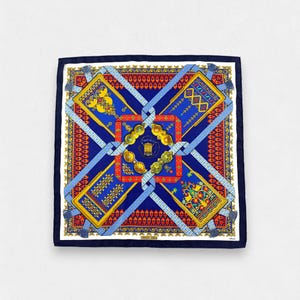 May include: A square silk scarf featuring a deep blue background with a central red square frame. The design includes four rectangular panels with intricate yellow and gold patterns, connected by light blue ribbons and gold circular ornaments.