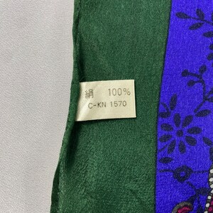 May include: A green and blue silk scarf with a floral pattern. The tag on the scarf reads "絹 100% C-KN 1570".