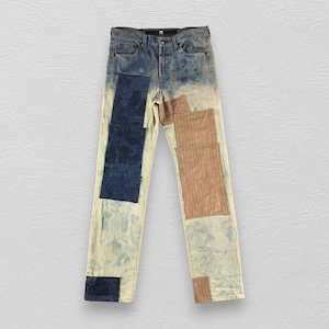 May include: Blue denim jeans with patches of brown and blue fabric. The jeans have a faded, distressed look.