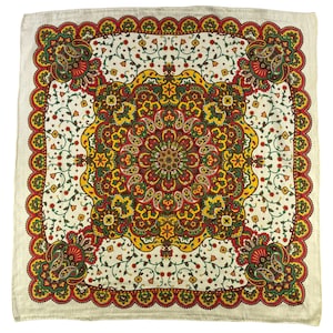 Op de afbeelding: Een vierkante sjaal met een centraal mandala-achtig patroon in tinten rood, geel, groen en bruin op een gebroken witte achtergrond. Het ontwerp bevat ingewikkelde paisley-motieven, florale elementen en een geschulpte rand met herhalende patronen.