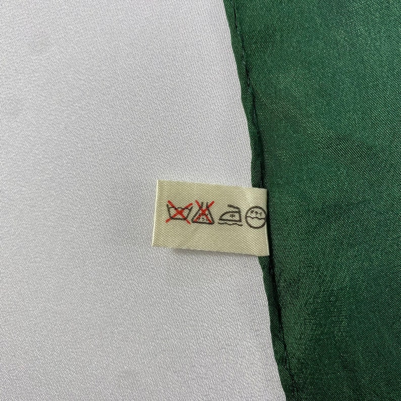 May include: A white care label with four symbols: a washing machine with a cross through it, an iron with a dot inside, a triangle with a cross through it, and a circle with a cross through it.