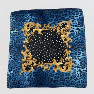 Pode incluir: Lenço quadrado de seda com fundo de estampa de leopardo azul. O centro apresenta um quadrado preto com estrelas brancas, emoldurado por um design dourado ornamentado. Um acessório luxuoso.