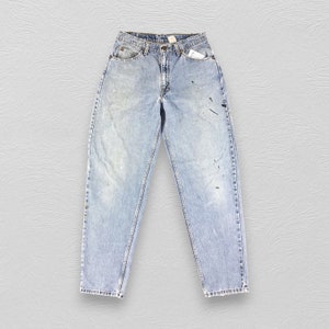 May include: Light blue denim jeans with faded spots and paint splatters. The jeans have a high waist and a straight leg.