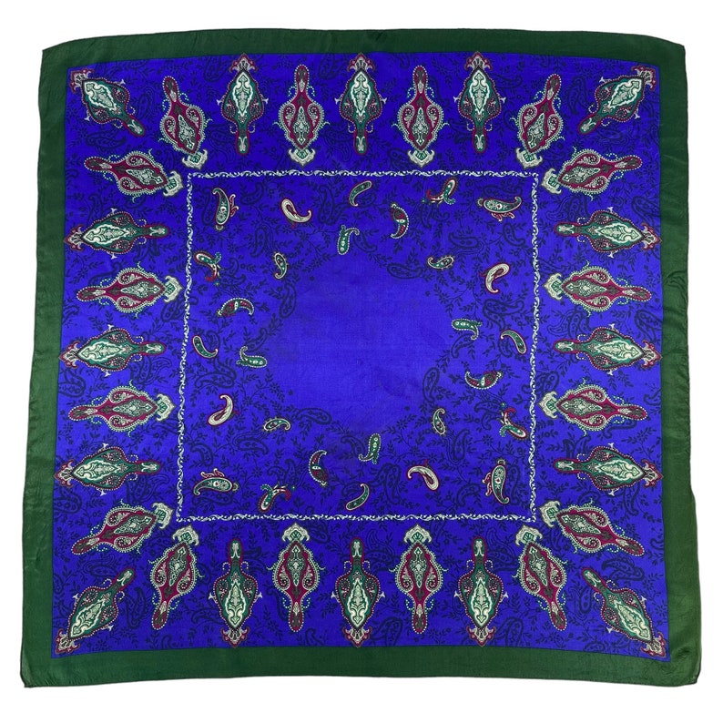 May include: A square blue silk scarf with a paisley pattern in shades of green, burgundy, and white. The scarf has a dark green border.
