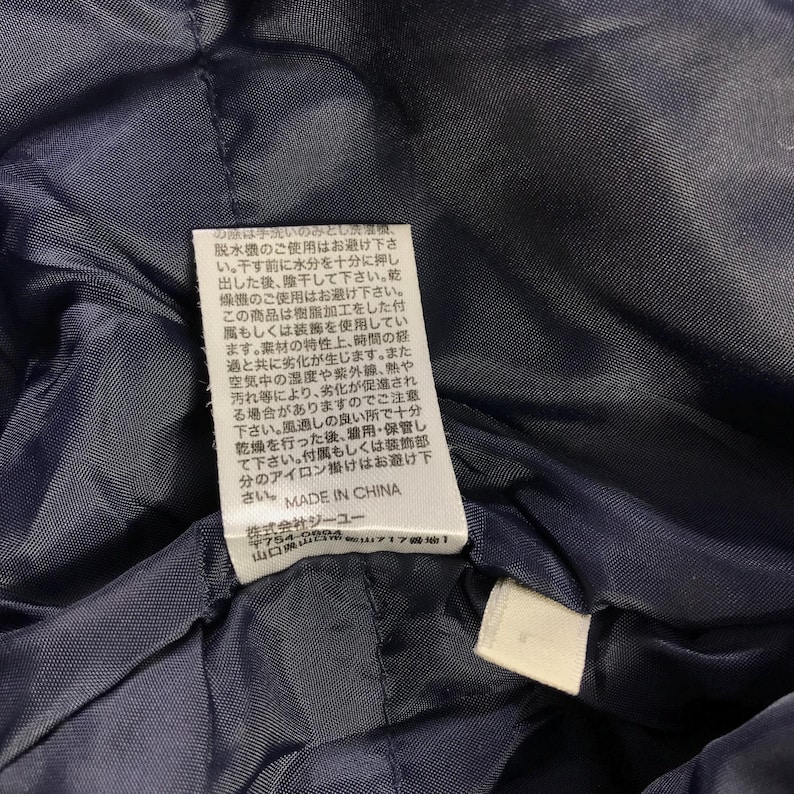 Puede incluir: Etiqueta blanca con texto negro que detalla las instrucciones de cuidado de una prenda. El texto dice: "Esta prenda se debe lavar solo a mano. No usar lavadora ni secadora. Secar en plano a la sombra. No usar lej&iacute;a. No planchar. Hecho en China."