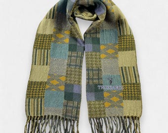 May include: A patchwork scarf in shades of green, blue, and yellow with a fringed edge. The scarf features various patterns, including plaid, houndstooth, and diamond designs. The brand name "TRUSSARDI" is embroidered on the scarf.