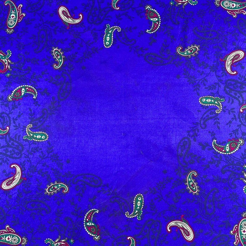 May include: A blue fabric background with a paisley pattern. The paisley pattern is in shades of green, red, and white.