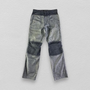 May include: A pair of blue denim trousers with multiple panels of different shades of blue denim. The trousers have a relaxed fit and a straight leg.