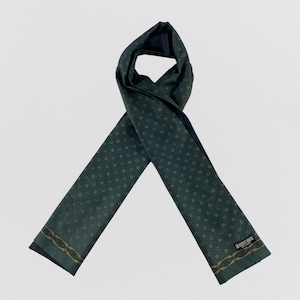 May include: A dark green scarf featuring a repeating pattern of small gold and black geometric shapes. The scarf has a decorative border with a gold and black intricate design near the ends and a black label reading Robert Bruno.