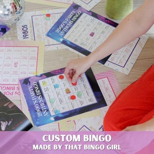 以下が含まれることがあります： 「2000's Party Anthems Bingo」および「1980s Icons Bingo」と書かれた複数の長方形のビンゴカード。カードはグリッドレイアウトで、印刷されたテキストと、特定のマスに配置されたカラフルな円形のマーカーが特徴です。デザインには、紫、青、ピンクのグラデーションとさまざまなグラフィック要素が含まれています。