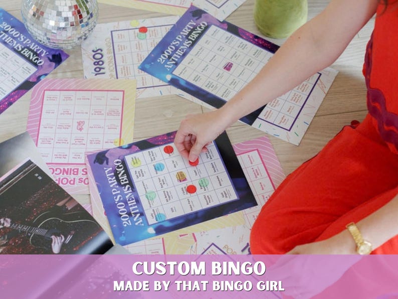 以下が含まれることがあります： 「2000's Party Anthems Bingo」および「1980s Icons Bingo」と書かれた複数の長方形のビンゴカード。カードはグリッドレイアウトで、印刷されたテキストと、特定のマスに配置されたカラフルな円形のマーカーが特徴です。デザインには、紫、青、ピンクのグラデーションとさまざまなグラフィック要素が含まれています。