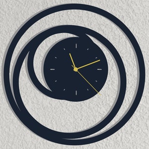 Könnte beinhalten: Eine schwarze und goldene Uhr mit einem runden Design. Das Zifferblatt der Uhr ist schwarz mit goldenen Zeigern und einem goldenen Ring am Rand. Die Uhr ist von zwei konzentrischen Kreisen umgeben, ebenfalls in Schwarz.