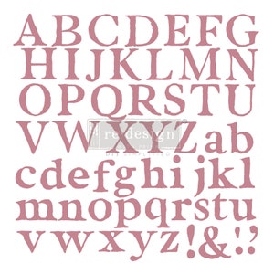 May include: A pink alphabet stencil with uppercase and lowercase letters, numbers, and punctuation marks. The stencil includes the letters A-Z, a-z, the numbers 1-9, and the punctuation marks !, &, and .?.