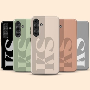 May include: A collection of five phone cases in various colors: black, sage green, beige, terracotta, and gray. Each case features the initials "KS" in a bold, stylized font. The cases have a vertical stripe design.