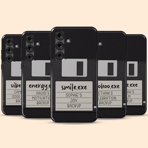 Peut inclure: Cinq coques de smartphone noires arborant un design graphique de disquette vintage. Chaque coque présente une étiquette blanche avec du texte personnalisé, incluant des noms de fichiers comme smile.exe et des noms comme Sophie's Joy Backup.